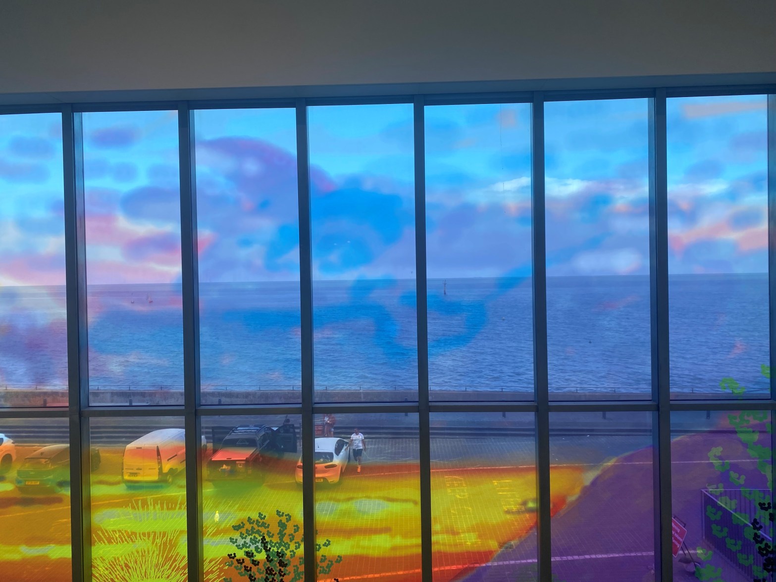 Image shows a painted window with the sea in visible through the window